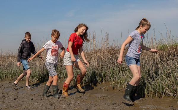 Kinderen lopen met laarzen door de modder