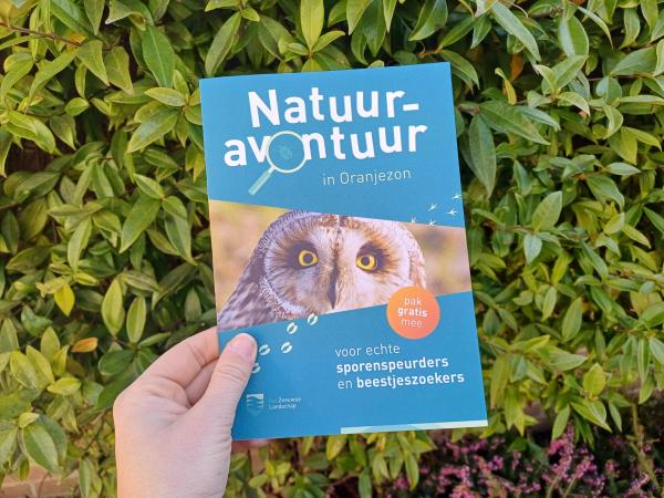 Natuuravontuurfolder vastgehouden tegen een groene achtergrond