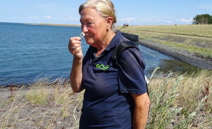Natuurgids Ine ruikt aan bloem