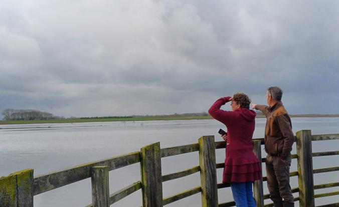 man en vrouw kijken op brug uit over water